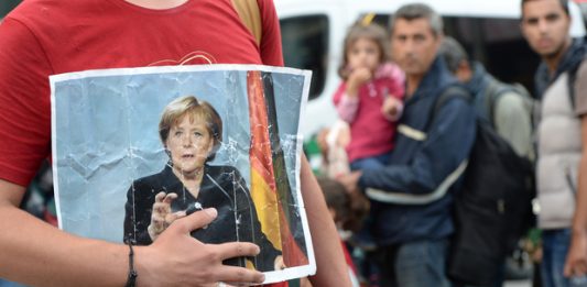 A refugee holds a picture of German Chancellor Angela Merkel