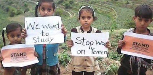 Children in Yemen hold signs up saying 'I want to study' and 'Stop war on Yemen'