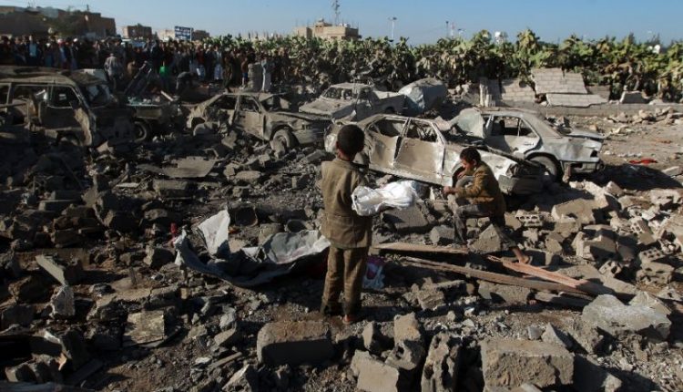 Yemenis stand at the site of a Saudi air strike against Huthi rebels near Sanaa Airport in March, 2015