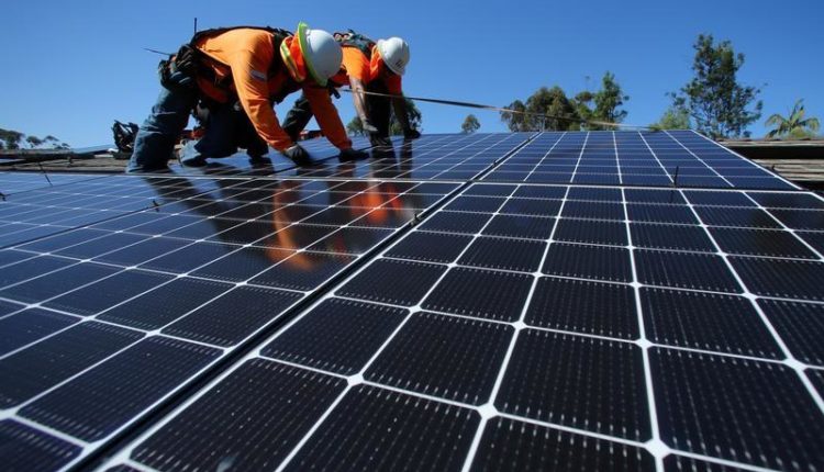 Solar installers place solar panels on the roof of a residential home in Scripps Ranch, San Diego, California, U.S.