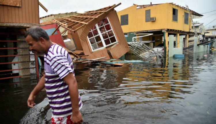 A men walks down a flooded street, where houses have collapsed, after Hurricane Maria had hit the island of Puerto Rico