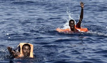 Two African shipwrecked migrants swimming toward a rescue boat in the Mediterranean Sea, off the coast of Libya