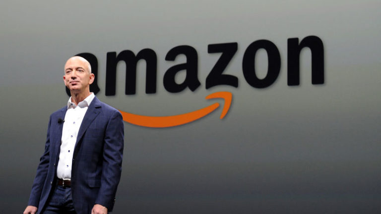 Jeff Bezos standing next to an Amazon sign