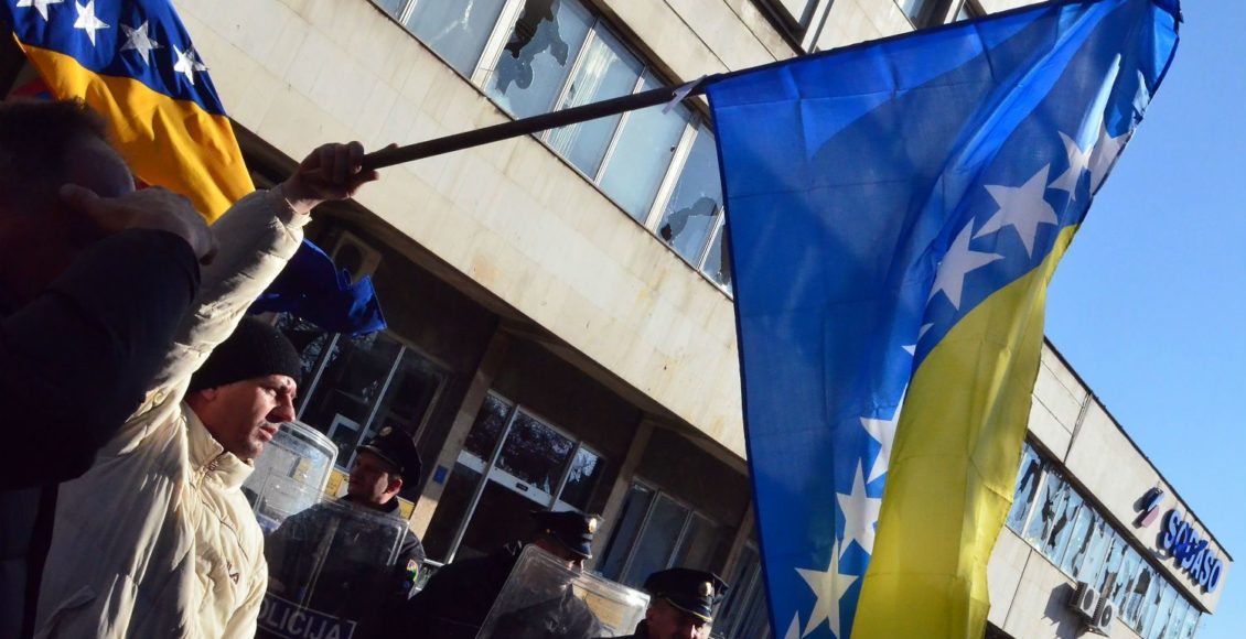 A demonstrator waves a Bosnian flag