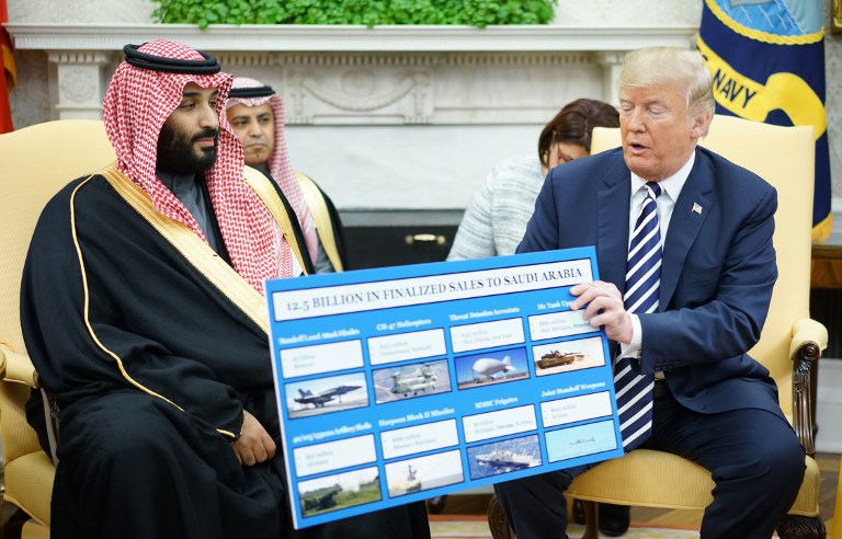 US President Donald Trump (R) holds a defense sales chart with Saudi Arabia's Crown Prince Mohammed bin Salman in the Oval Office of the White House on March 20, 2018 in Washington, DC