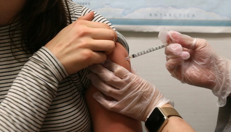 A girl gets a flu vaccine in her upper arm.