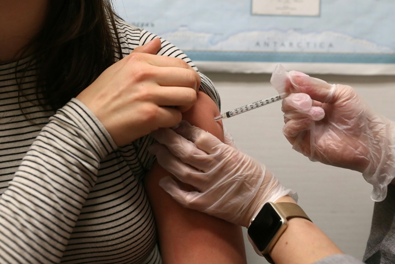 A girl gets a flu vaccine in her upper arm.