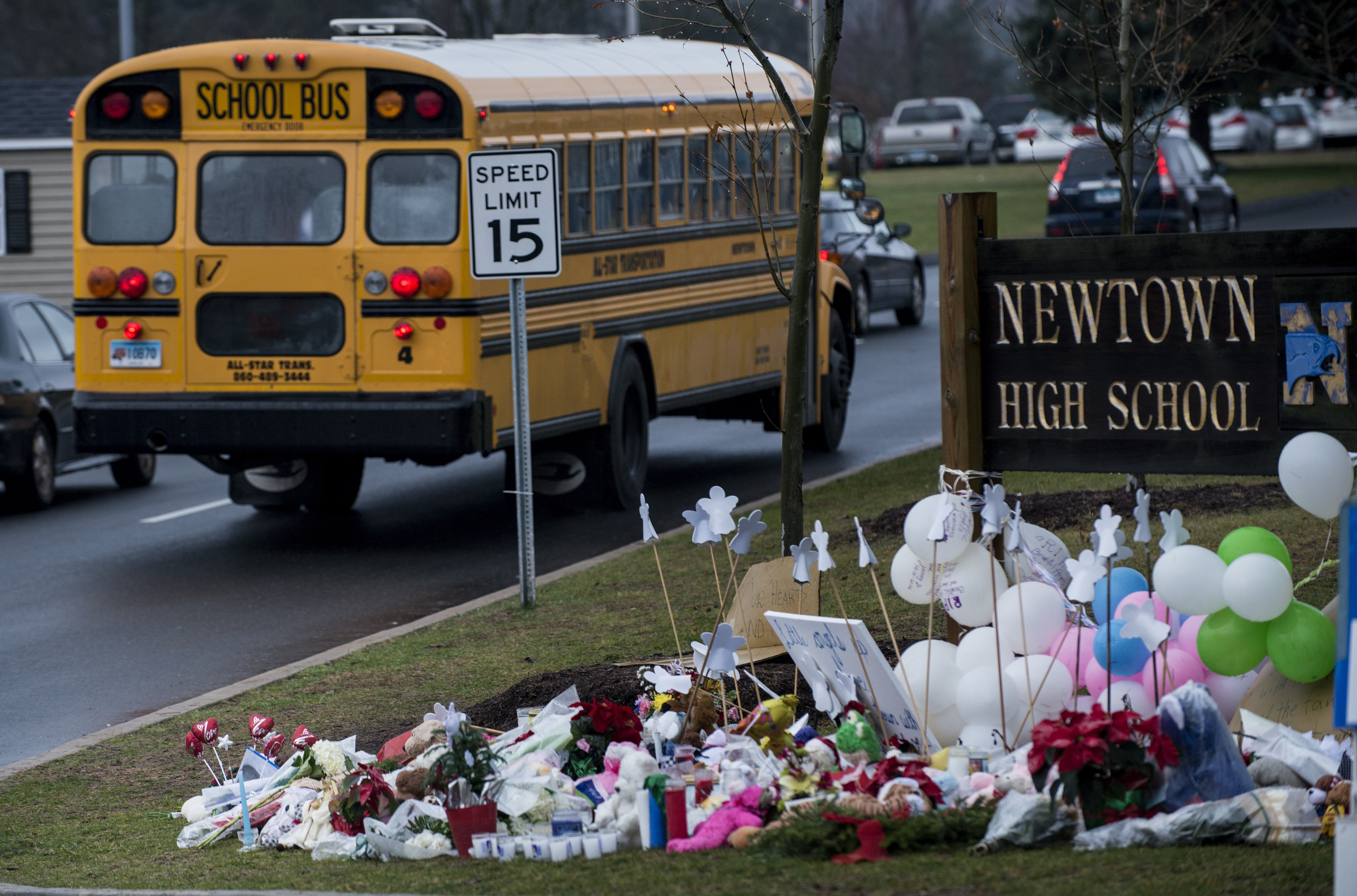 A school bus passes a makeshift memorial to the victims of the Sandy Hook Elementary School shooting as it takes students to Newtown High School December 18, 2012 in Newtown, Connecticut.