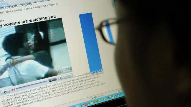 A men looking at his computer screen saying 'voyeurs are watching you'