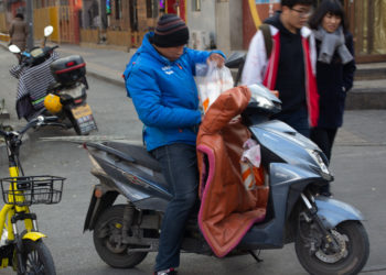 A Chinese food delivery person on a motorbike