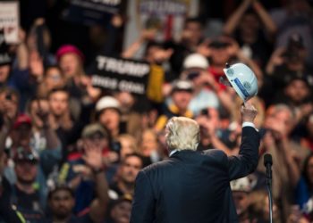 Donald Trump holds a miner's helmet up after speaking during a rally