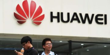 Two men stand in front of a Huawei store in Beijing, China