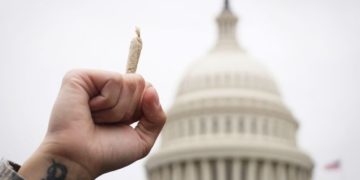 A pro-cannabis activist holds up a marijuana cigarette during a rally on Capitol Hill