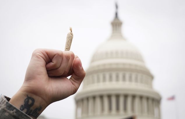 A pro-cannabis activist holds up a marijuana cigarette during a rally on Capitol Hill