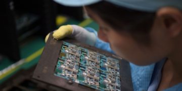 A worker handles smartphone chip components at a factory in Dongguan, China