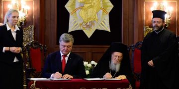 Ukraine's president Petro Poroshenko (L) and Ecumenical Patriarch of Constantinople Bartholomew (R) sign an agreement during their meeting at the Fener Greek Patriarchate in Istanbul on November 3