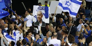 Supporters of the Israeli Likud Party wave party and national flags as they gather at its headquarters in the coastal city of Tel Aviv on election night early on April 10, 2019
