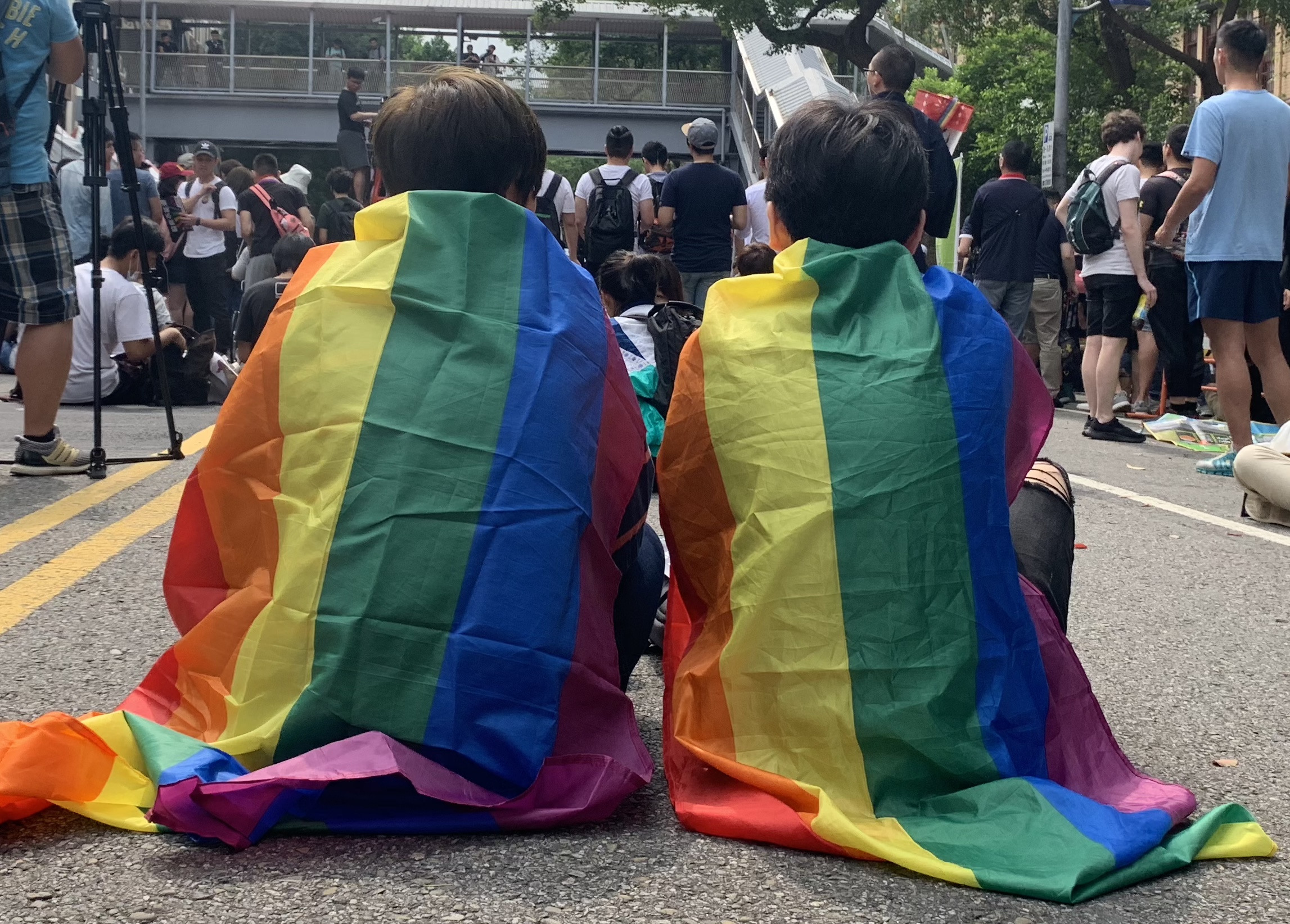 Two LGTB rights supporters covered in rainbow flags attend Taipei's same-sex marriage gathering