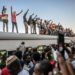 Sudanese protesters from the city of Atbara, flash the V-sign for victory and wave national flags atop a train, as it arrives at the Bahari station in Khartoum