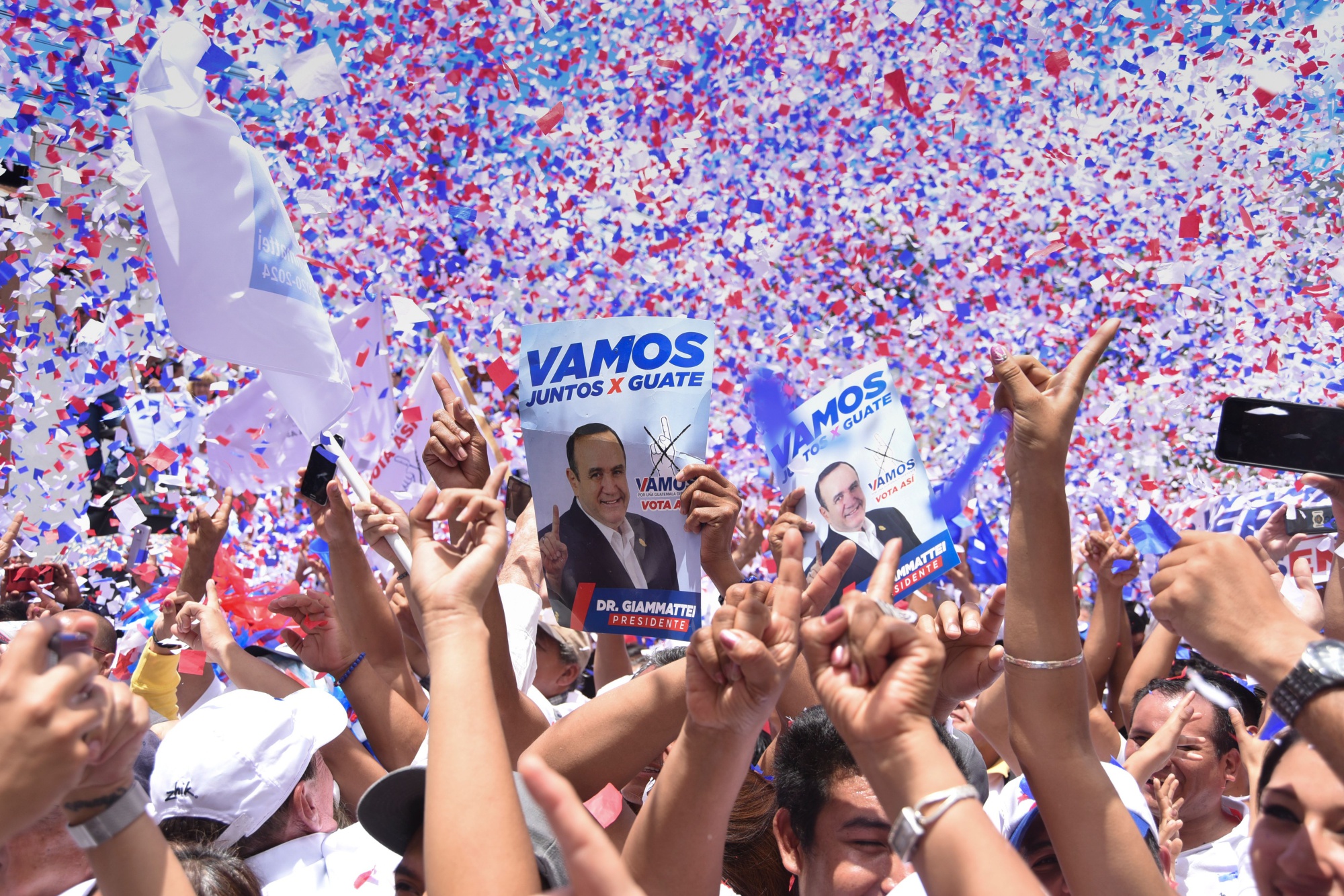 Vamos party supporters hold up posters of Alejandro Giammattei in Guatemala City on August 4