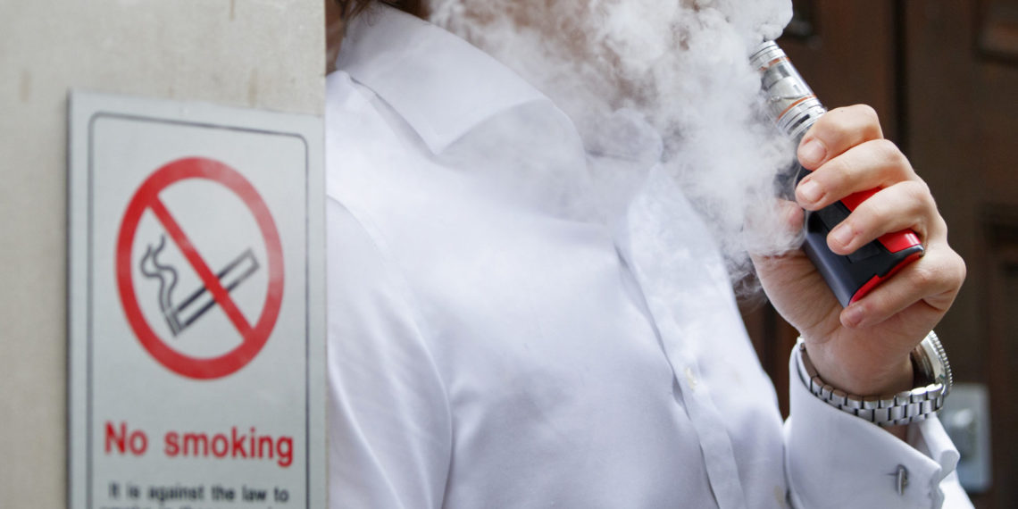 A smoker is engulfed by vapours as he smokes an electronic vaping machine during lunch time in central London on August 9, 2017.