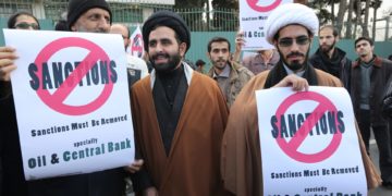 Iranian men hold placards reading 'Sanctions must be removed' in the capital Tehran on November 23, 2014