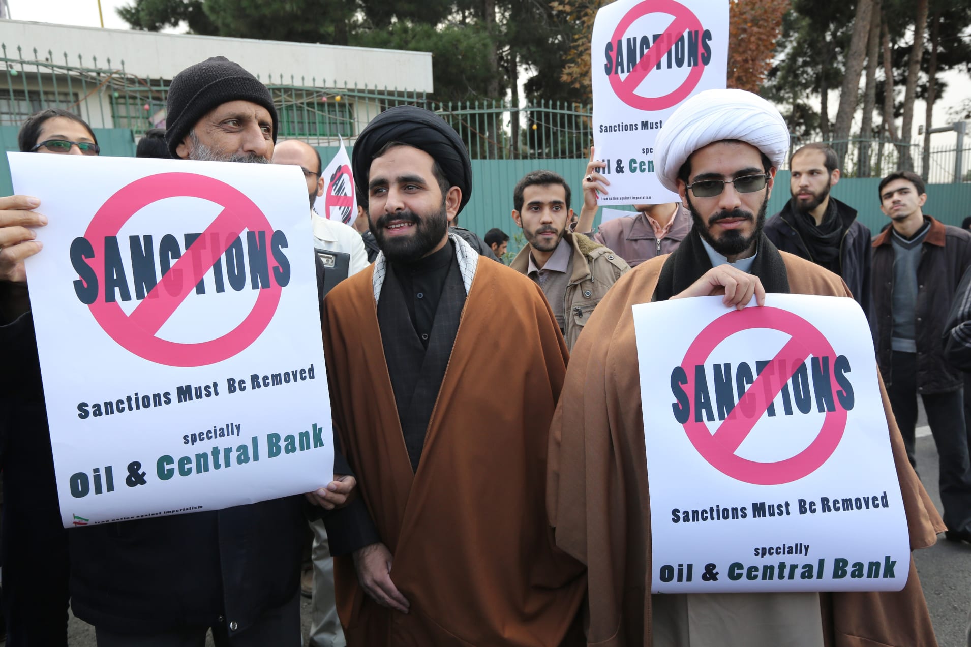 Iranian men hold placards reading 'Sanctions must be removed' in the capital Tehran on November 23, 2014