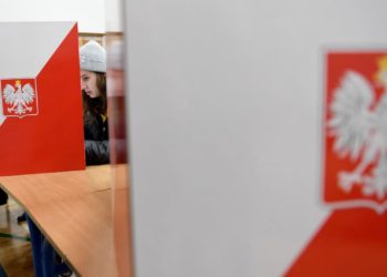 Voters check lists at a polling station during the first round of the local elections on October 21, 2018 in the Polish capital Warsaw