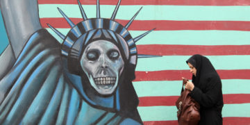 An Iranian woman walks past an anti-US mural painted on the wall of the former US embassy in Tehran on November 19, 2011