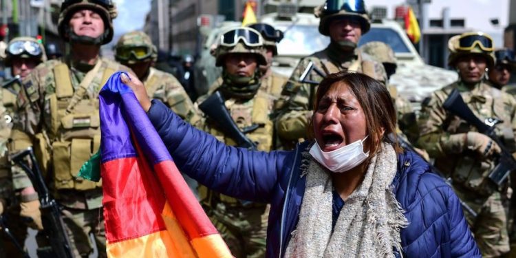 A Bolivian woman stands in front of a security forces at a mostly indigenous protest on November 16, 2019 against the coup that deposed President Evo Morales. Photo: AFP