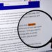 A magnifying glass emphazises the words 'fake news' on a computer screen.