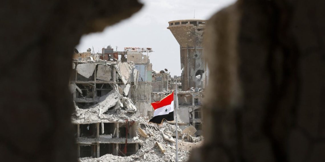 A Syrian government flag flies above the rubble in the neighbourhood of Hajar al-Aswad near Yarmouk refugee camp on the outskirts of Damascus, Syria