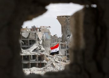 A Syrian government flag flies above the rubble in the neighbourhood of Hajar al-Aswad near Yarmouk refugee camp on the outskirts of Damascus, Syria