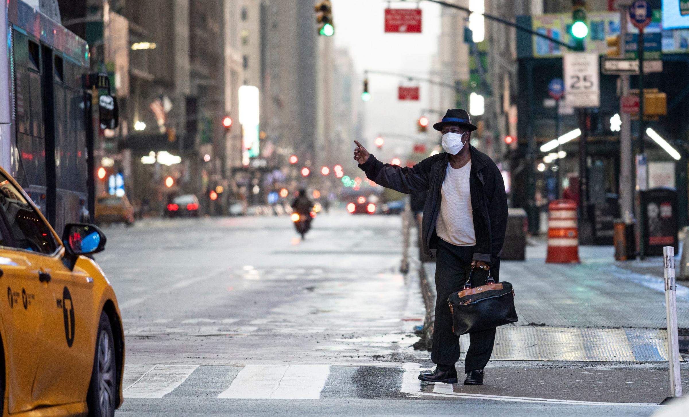 A man wearing a mask tries to catch a taxi at Times Square amid the COVID-19 pandemic on April 30, 2020 in New York City