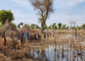 Children stand among the rooftops of homes after the Yusuf Batir refugee camp in South Sudan was hit by flooding, November 2019