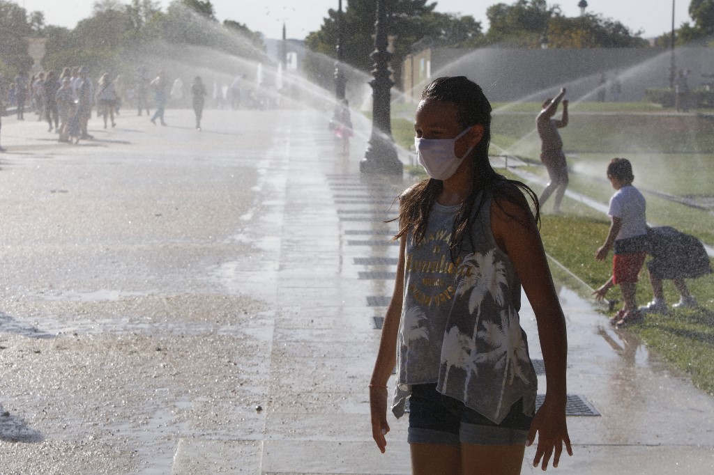 Tourists refresh themselves with water at the Jardin des Tuileries during a warm afternoon in Paris on July 19, 2020