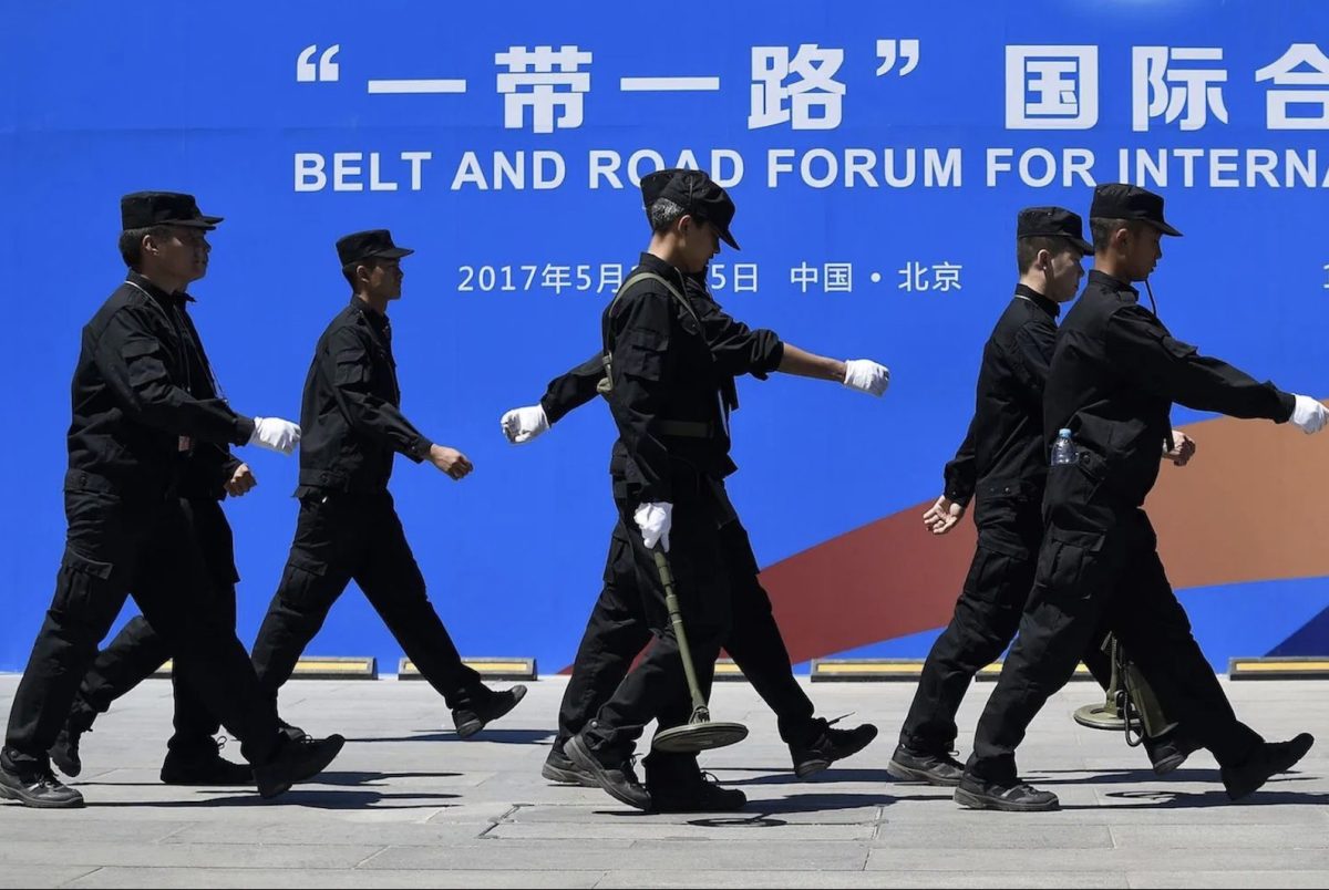 Security guards walk past a billboard for the Belt and Road Forum for International Cooperation in Beijing on May 13, 2017