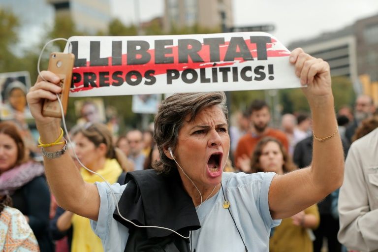 An angry protester holds a banner saying "Free political prisoners."
