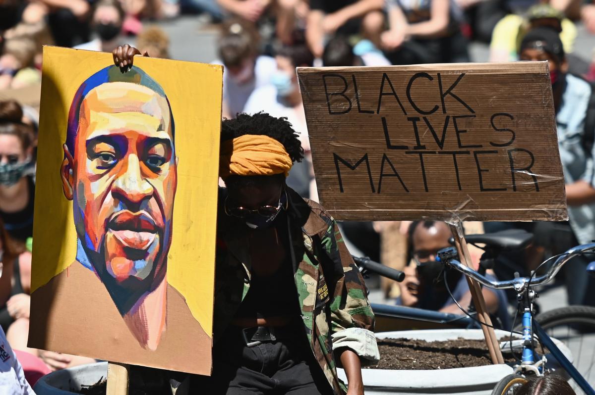 A protester holds a portrait of George Floyd.