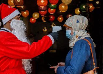 A Palestinian employee dressed as Santa Claus takes a customer's temperature at a cafeteria in Gaza City.