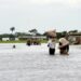 People carry their belonging on their heads while they walk on a flooded road following heavy rain downpour in Wawa in Ogun State southwest Nigeria