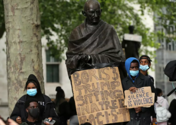 Protesters stand with placards in front of the statue of India's independence leader Mahatma Gandhi in Parliament Square, central London, after a demonstration outside the US Embassy