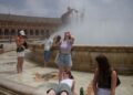 People cool off with a fountain's water during a heat wave in Seville, Spain