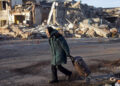 An elderly woman pulls a trolley bag past a destroyed building in Bakhmut in Ukraine's Donetsk