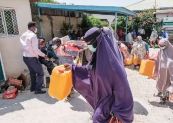 Ethiopian migrants hold items as they walk out during an assistance packages distribution for migrants at an International Organization for Migration (IOM) center in the city of Hargeisa, Somaliland