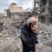 An Iranian man speaks on a cell phone and walks past the ruins of buildings that are destroyed during the U.S.-Israeli military campaign that strikes a residential area on March 9, in Tehran, Iran, on March 12, 2026.